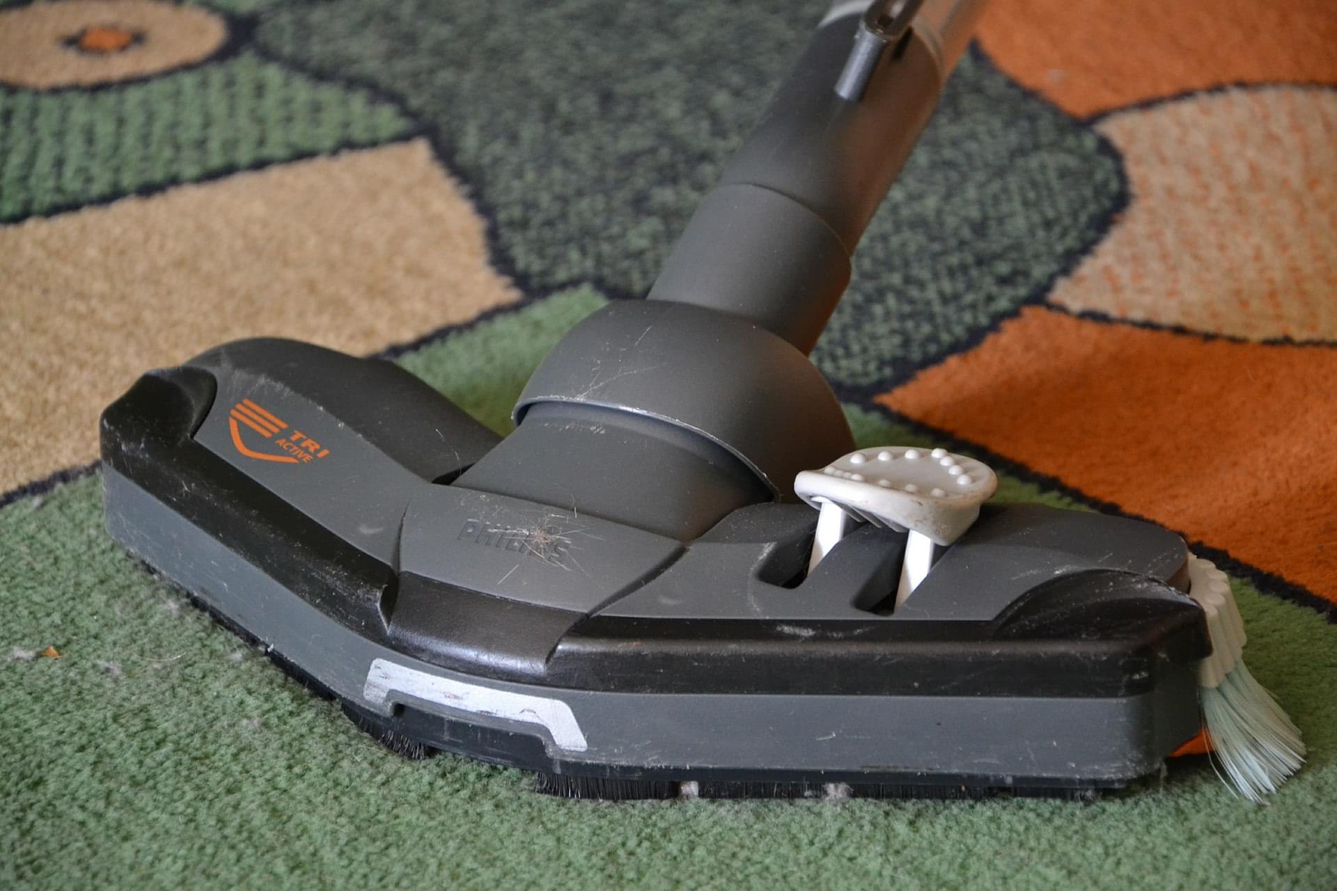 Colorful carpet being cleaned with a vacuum.